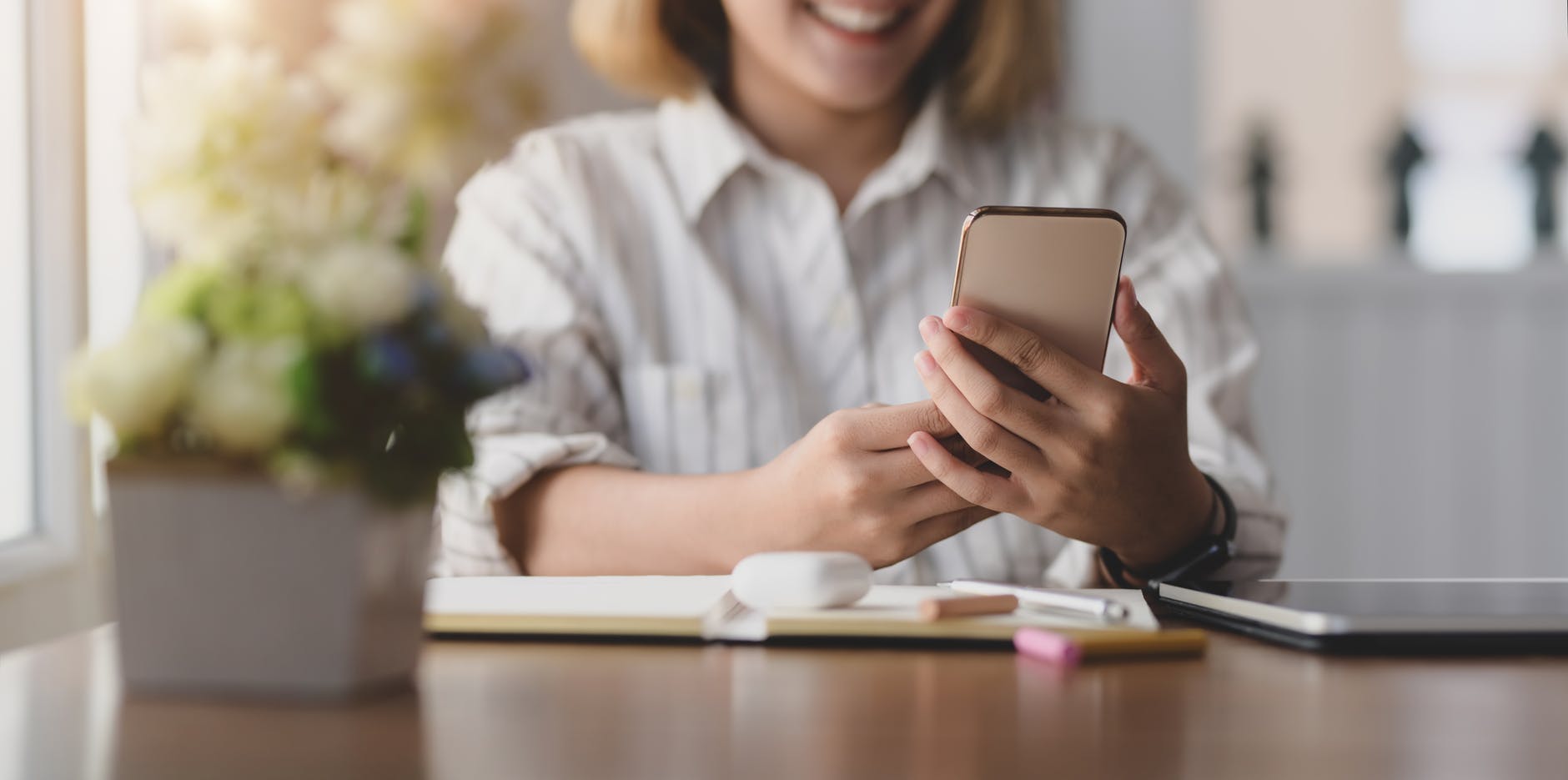 selective focus close up photo of smiling woman in white shirt using a phone